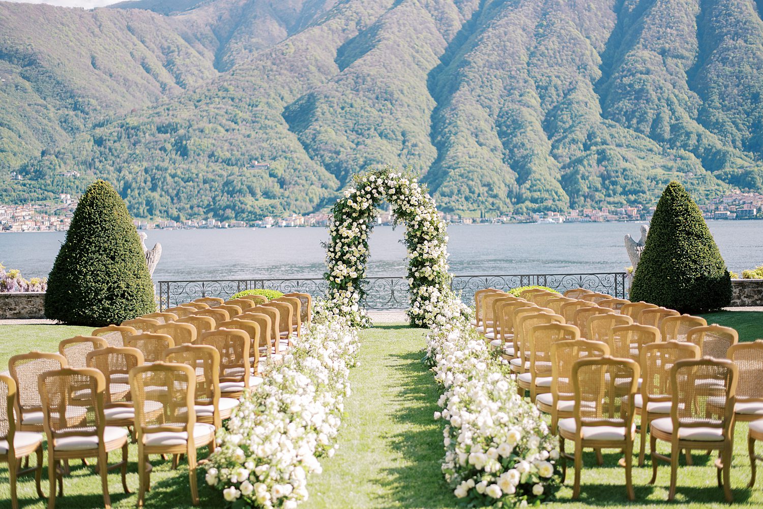 ceremony on lawn of Villa Balbiano with white roses lining aisle 