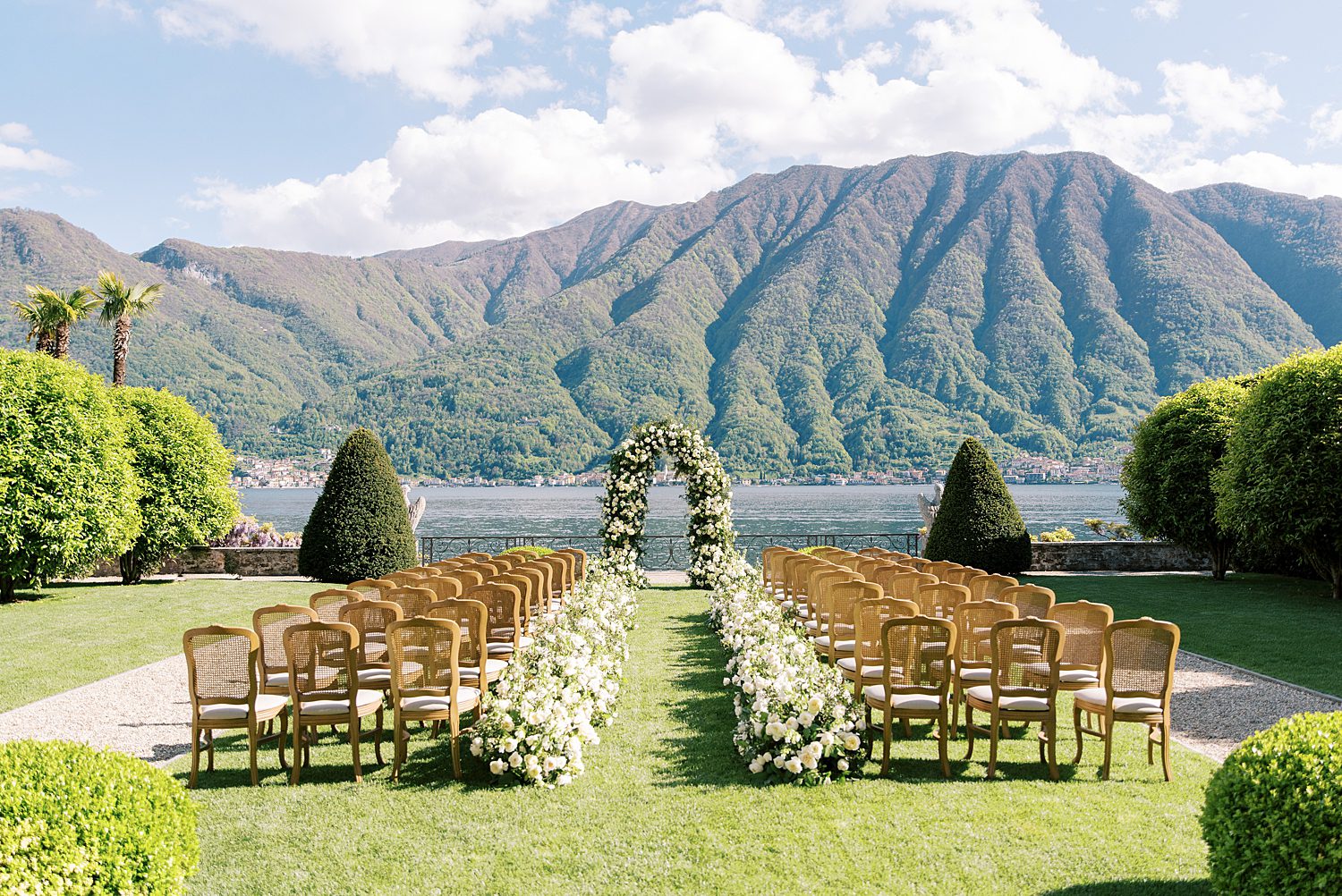 ceremony on lawn in front of Lake Como at Villa Balbiano with white flower arch