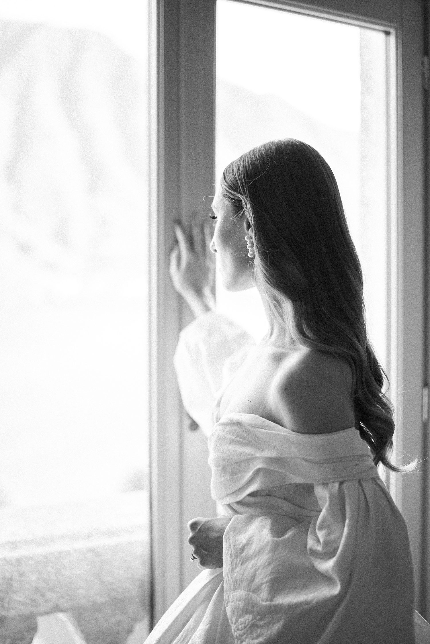 bride looks out window in off-the-shoulder wedding gown at Villa Balbiano