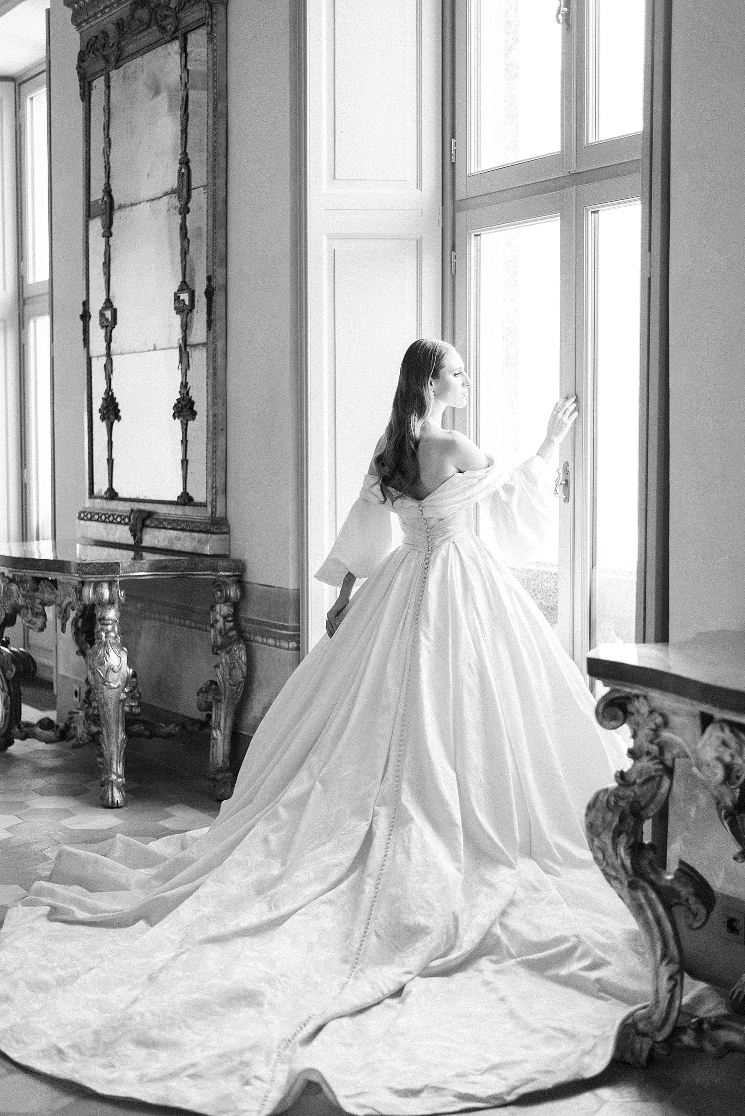 bride stands in window of Villa Balbiano in wedding gown designed by Ines Di Santo
