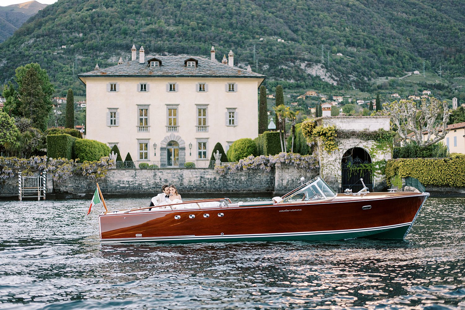 boat on Lake Como with bride and groom in front of Villa Balbiano