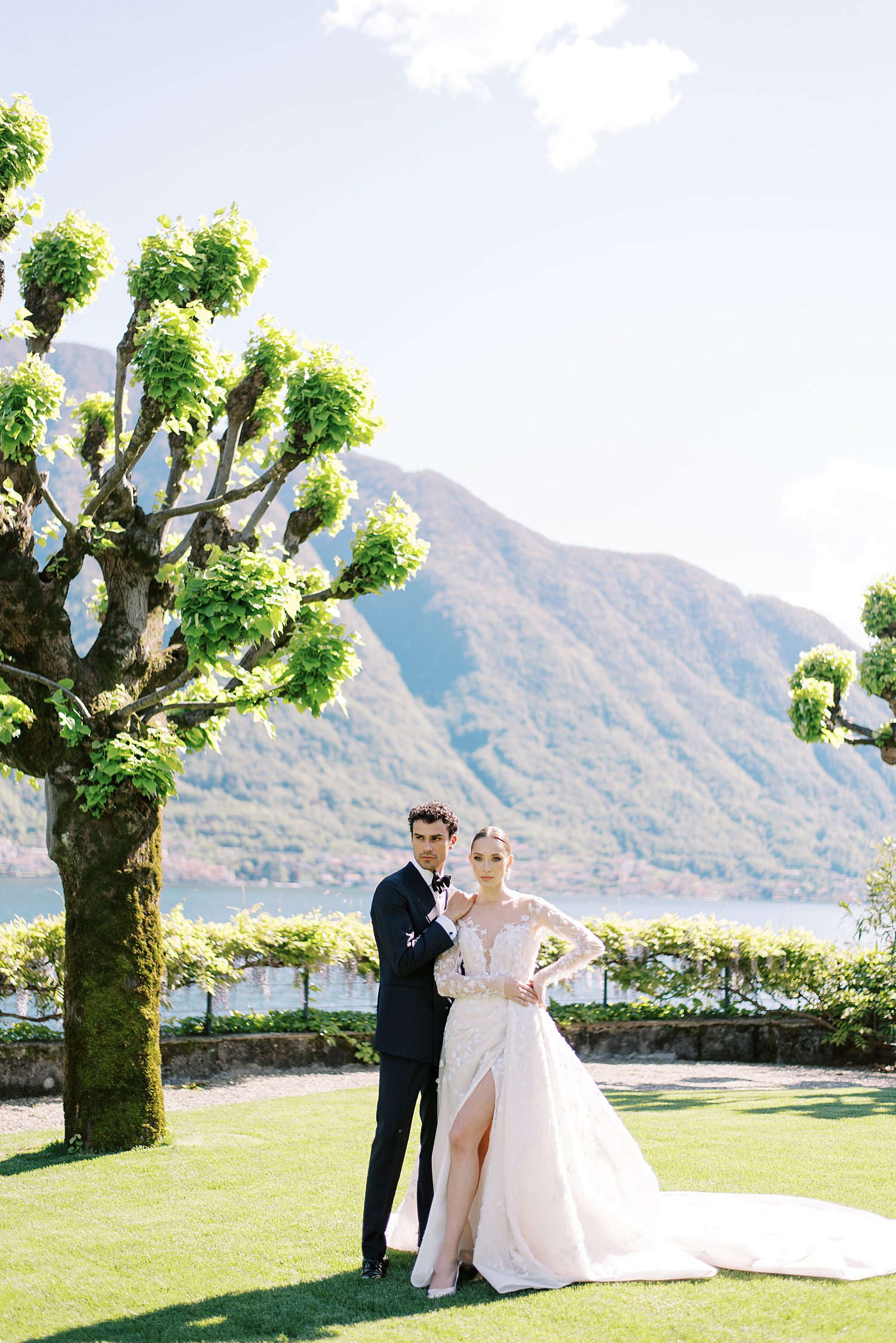 bride and groom hug on lawn at Villa Balbiano near tall tree