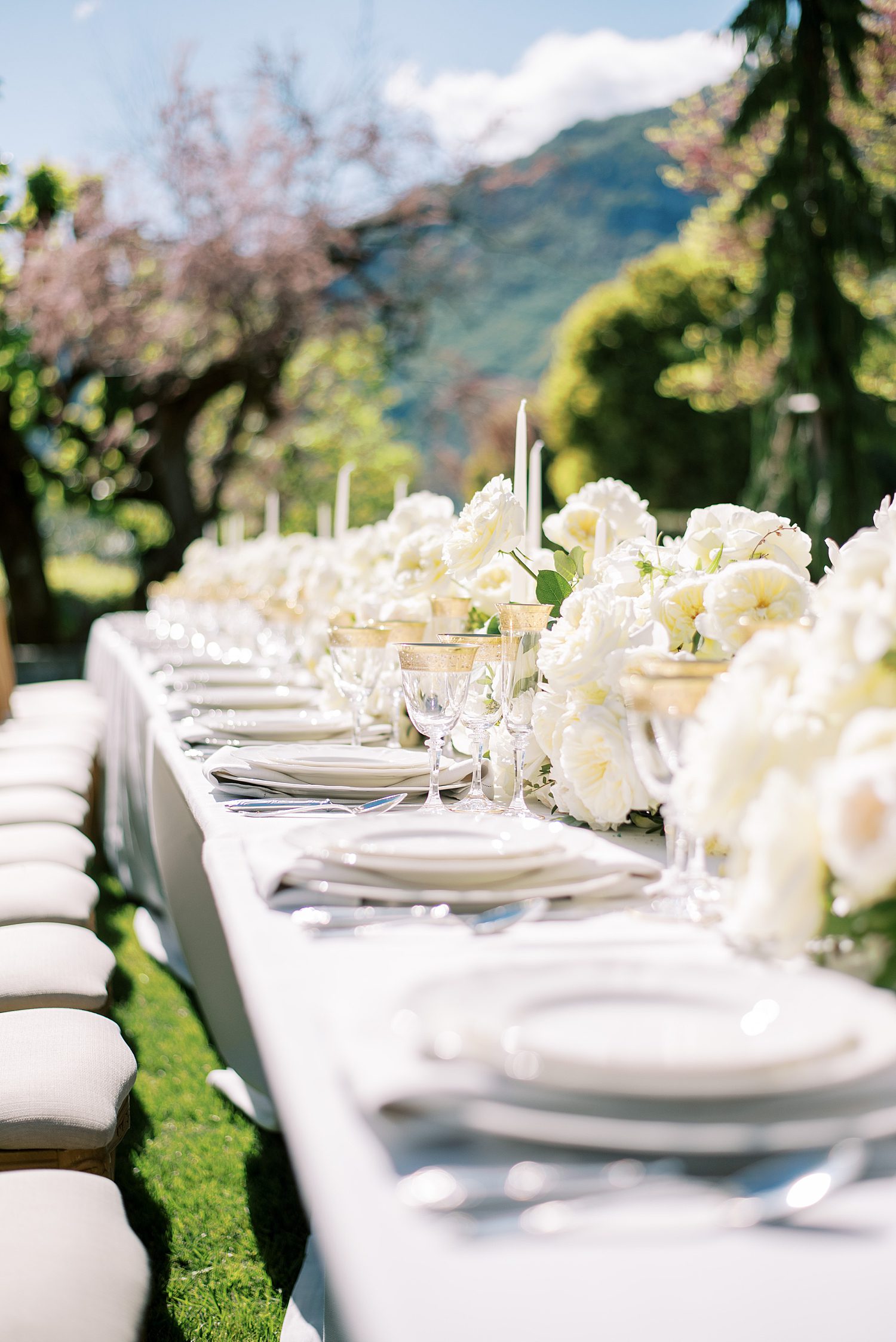 place settings in front of ivory roses on long table at Villa Balbiano