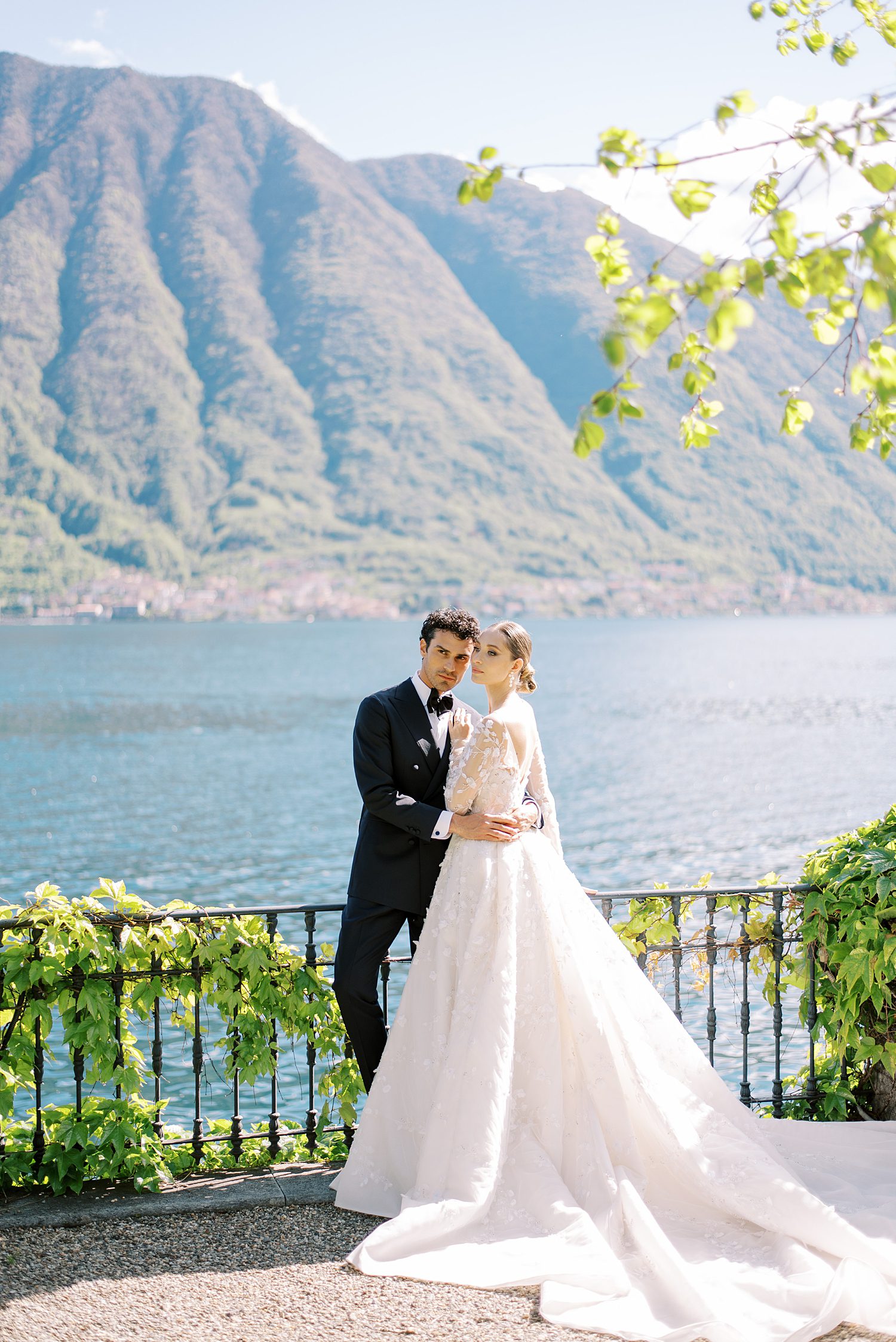 bride and groom stand on balcony in front of Lake Como