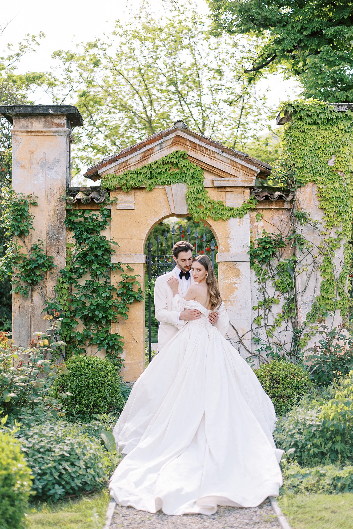 bride and groom hug in front of ivory wall outside Villa Balbiano