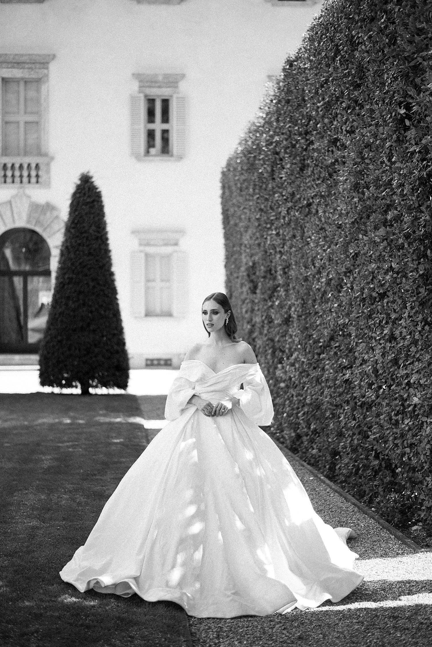 bride in wedding gown with full skirt walks through hedges at Villa Balbiano