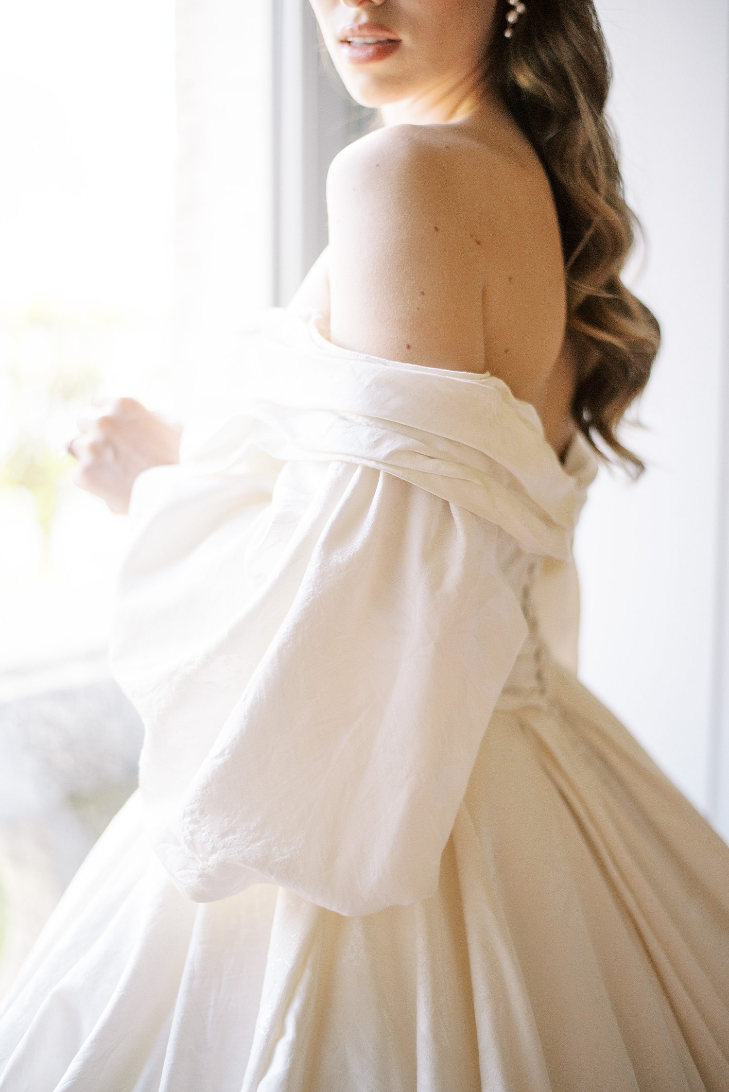 brunette bride stands in off-the-shoulder gown at Villa Balbiano