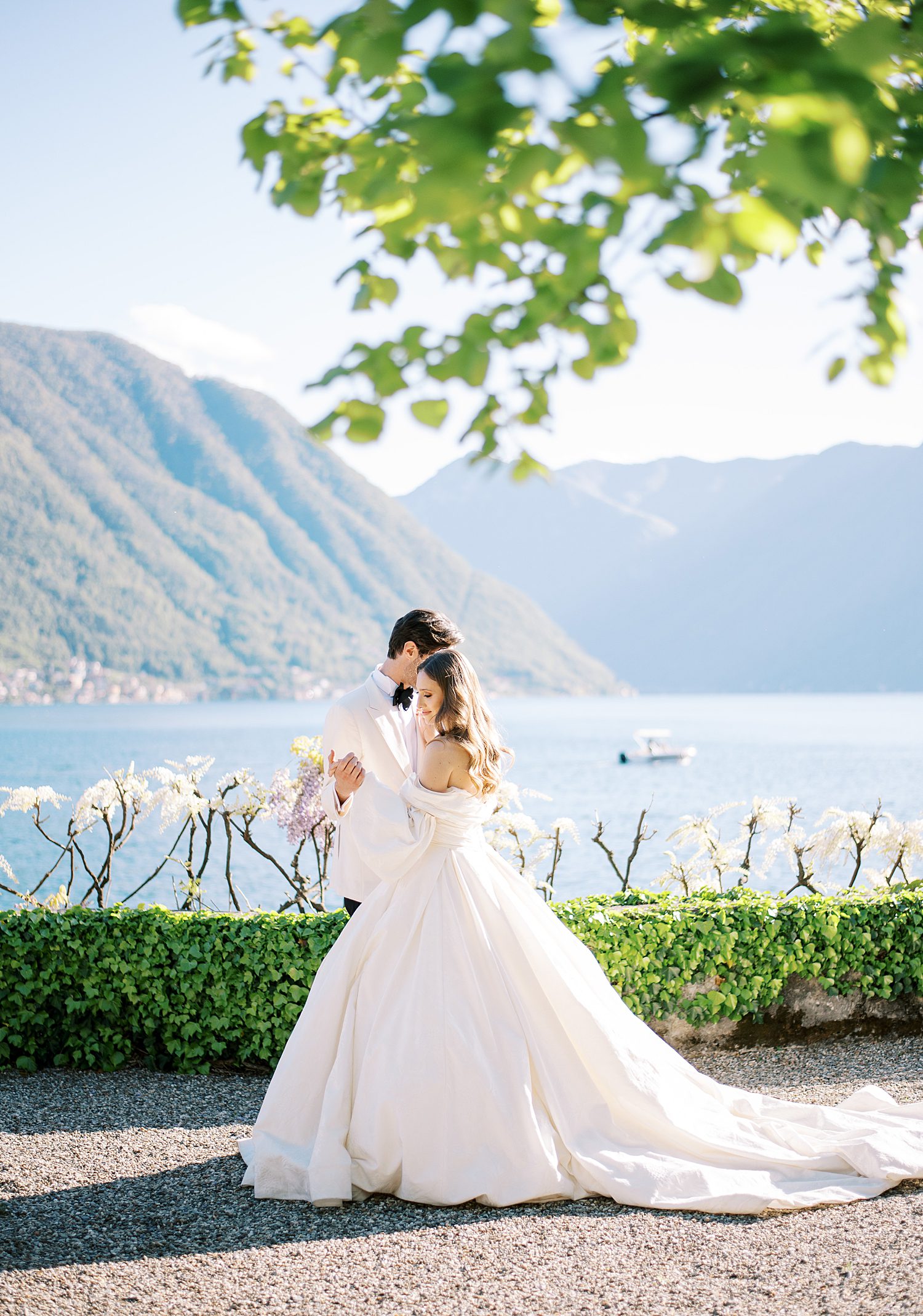 bride and groom hug facing lake Como on lawn at Villa Balbiano