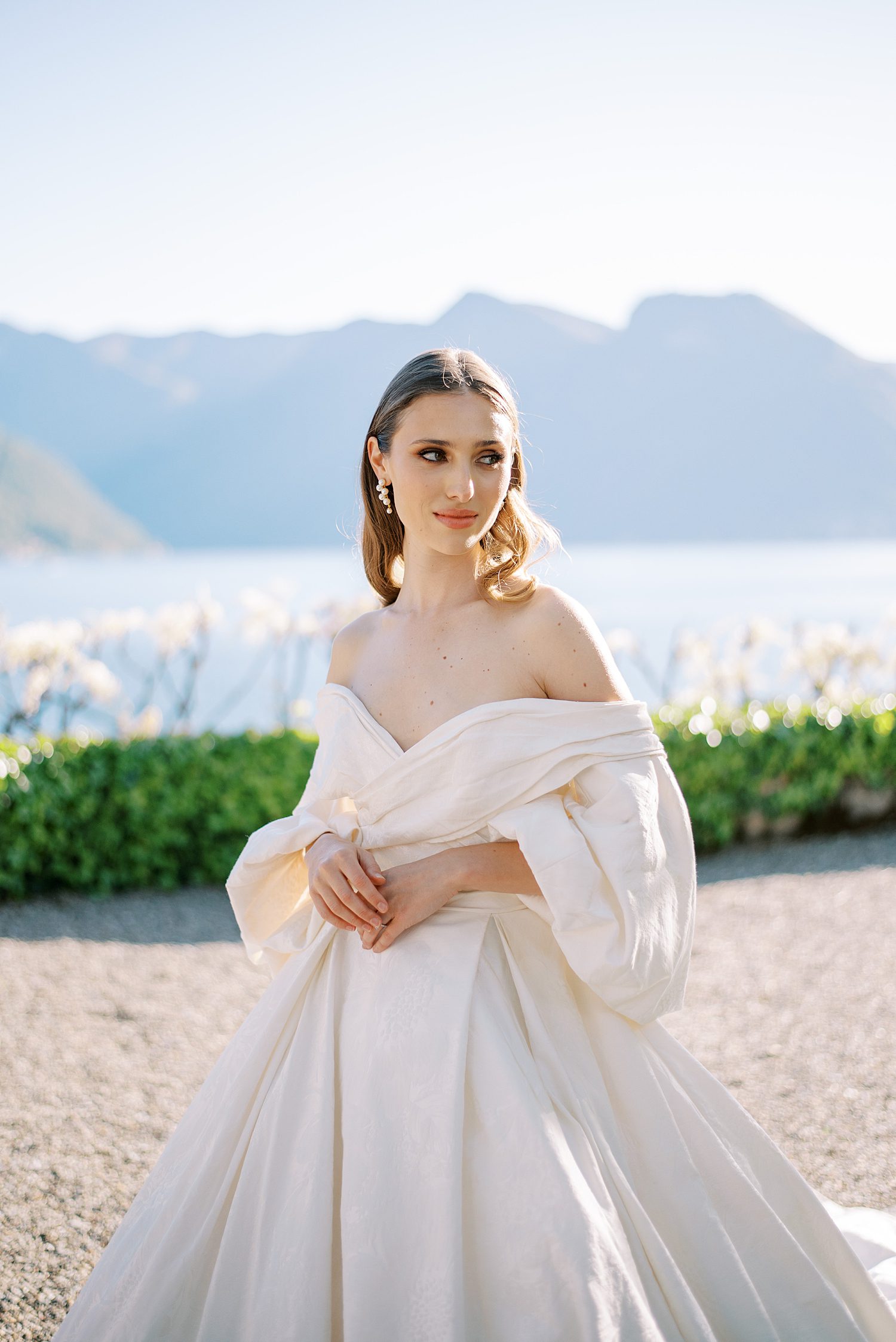 bride stands in wedding gown in front of Lake Como at Villa Balbiano
