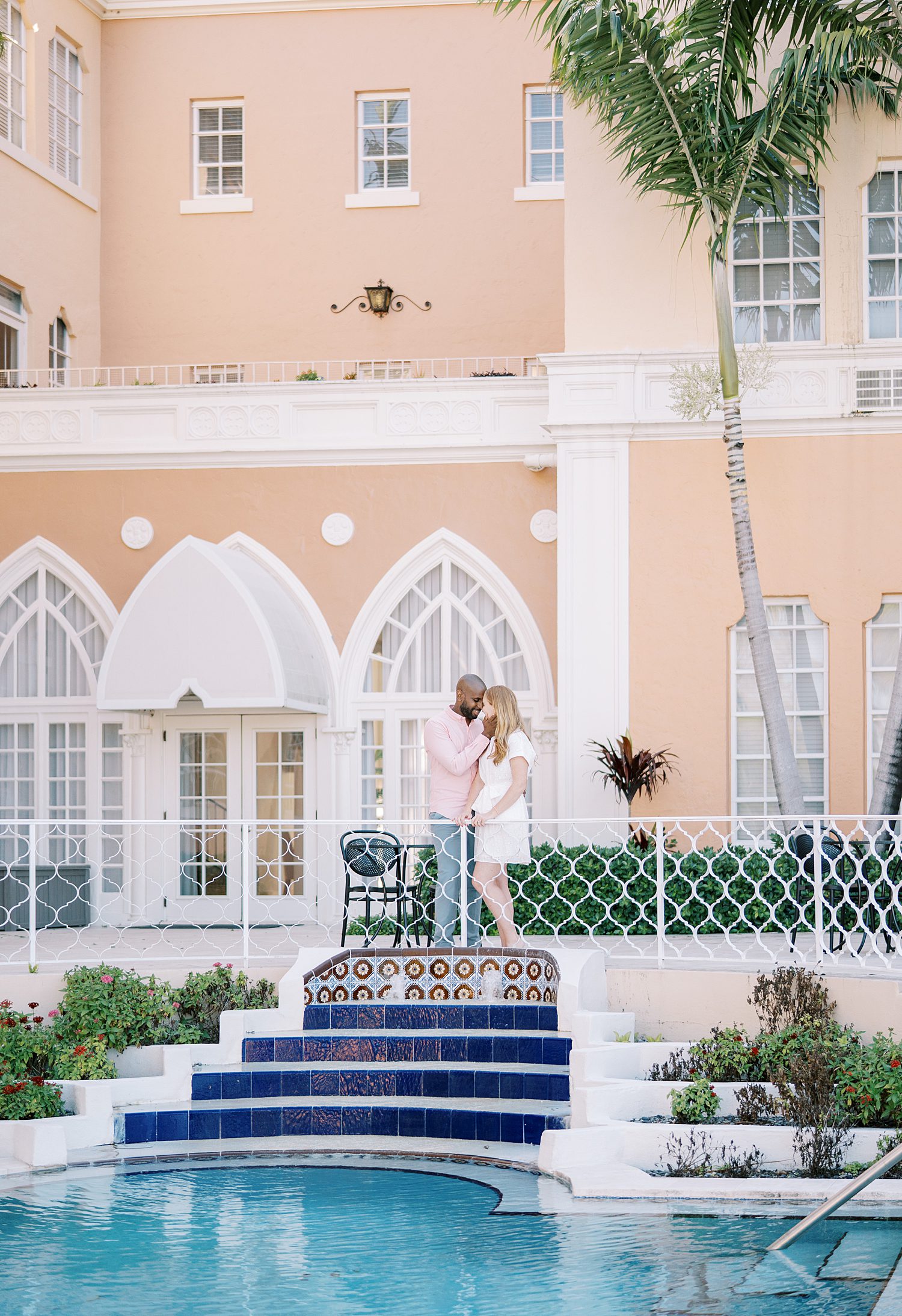 engaged couple stand on top of blue steps near pool in Tampa FL