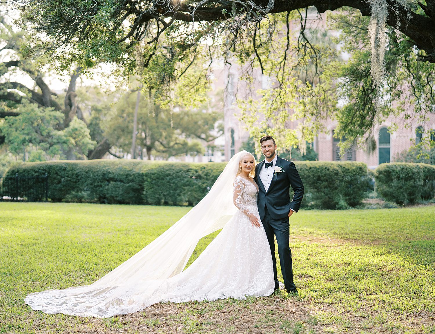 bride and groom hug under tree with Spanish moss in Tampa FL