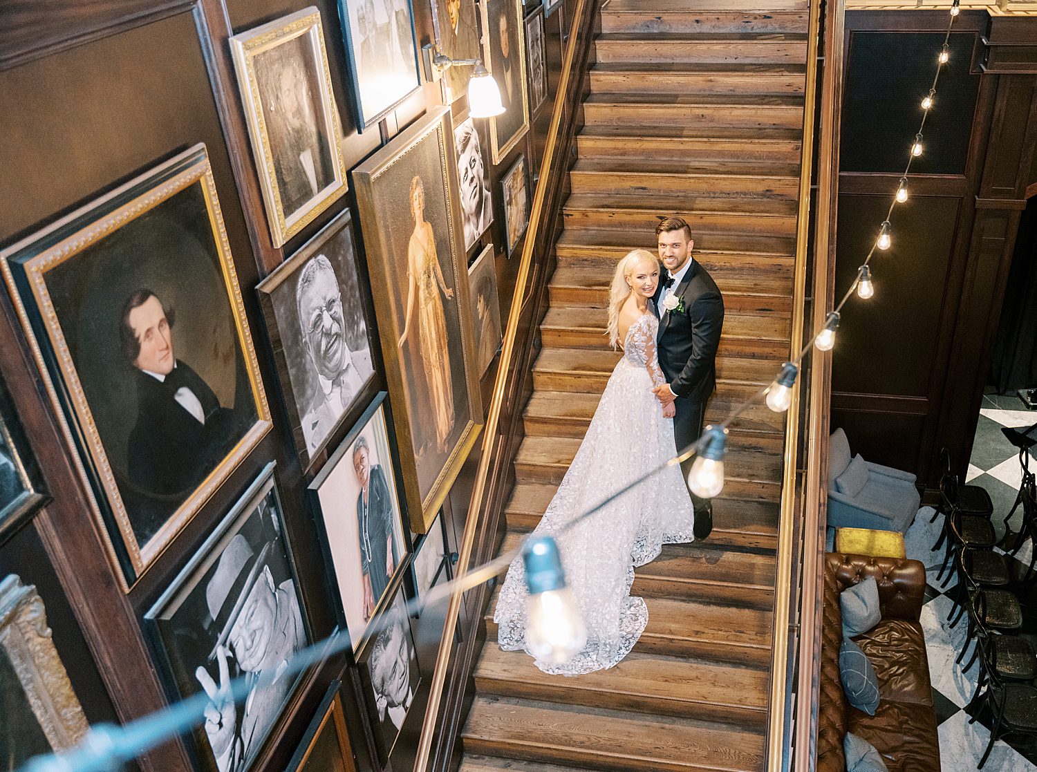 newlyweds pose on staircase inside the Oxford Exchange under patio lights 