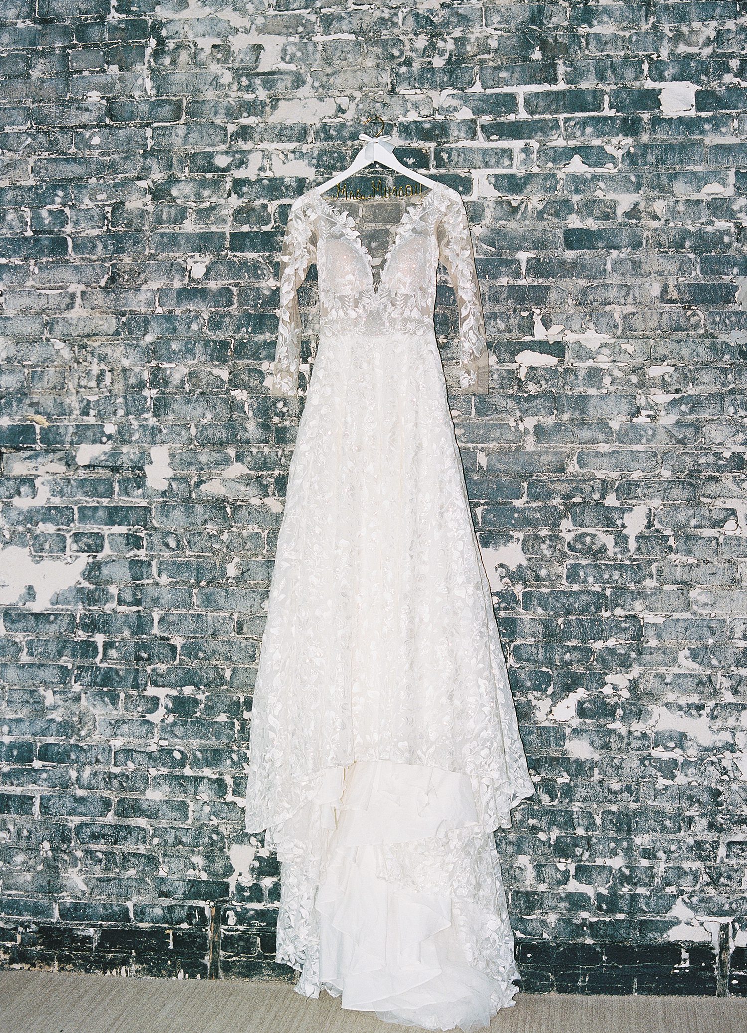 wedding dress with lace sleeves hangs on brick wall inside the Oxford Exchange