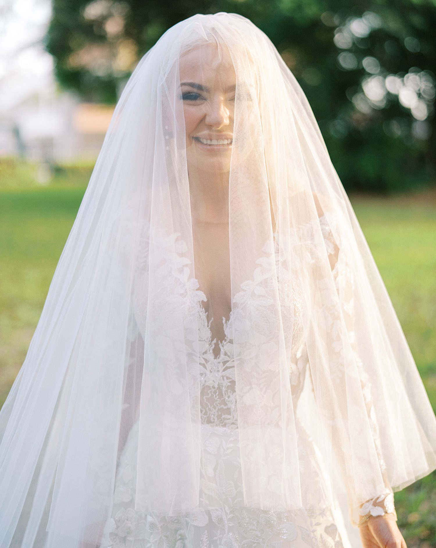 bride stands with veil over her head as she laughs 