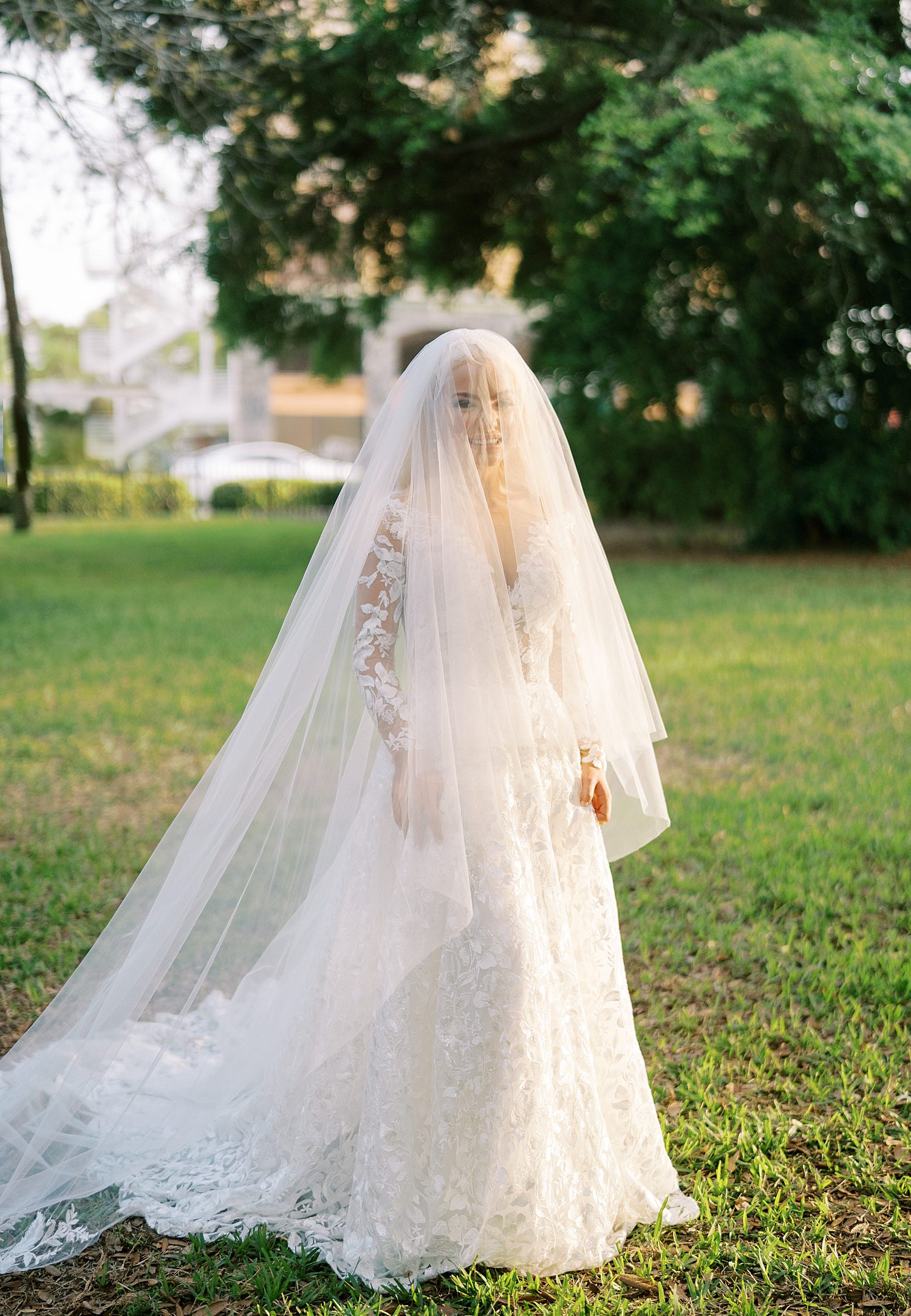 bride walks across lawn with veil over her head outside the Oxford Exchange