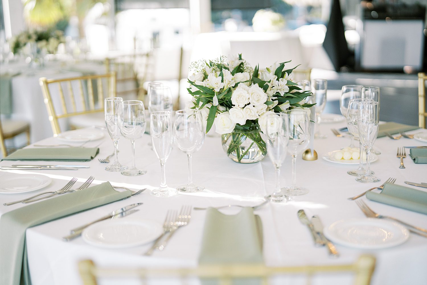 place setting with sage green napkins and ivory floral centerpiece at the Rusty Pelican Tampa