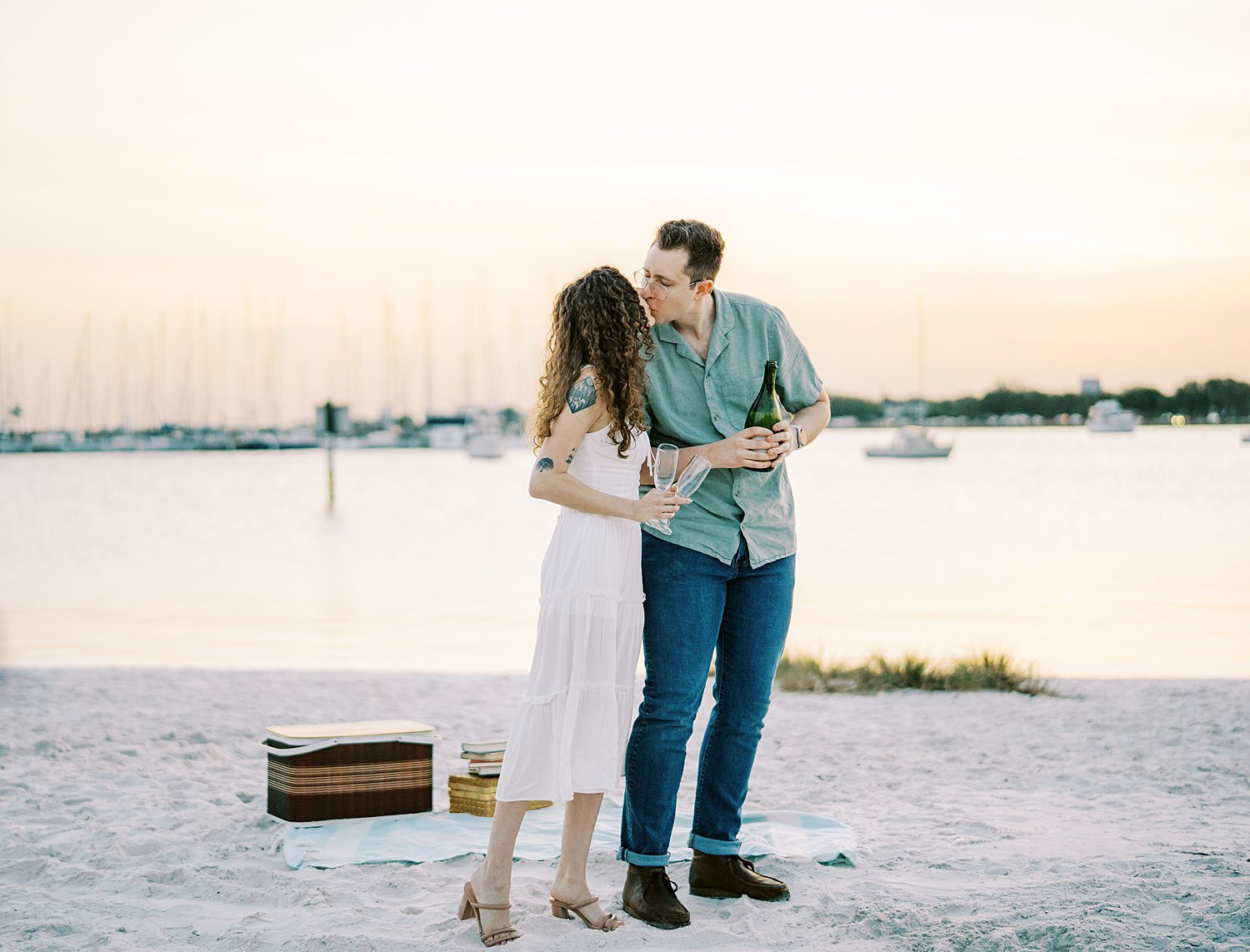 man and woman lean in for kiss holding glasses of champagne on Davis Island Beach 