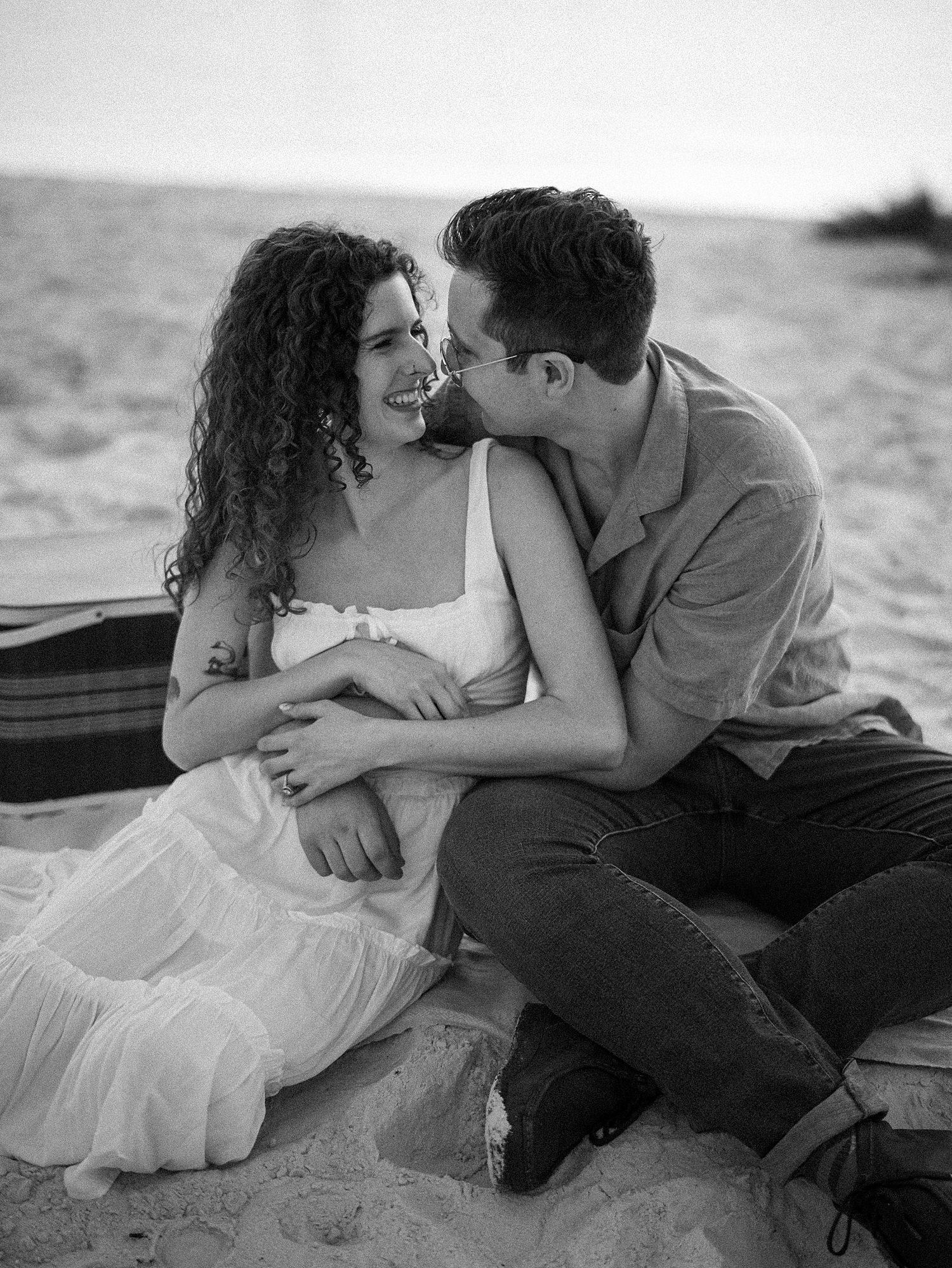 man hugs woman in white sundress during picnic on Davis Island beach 