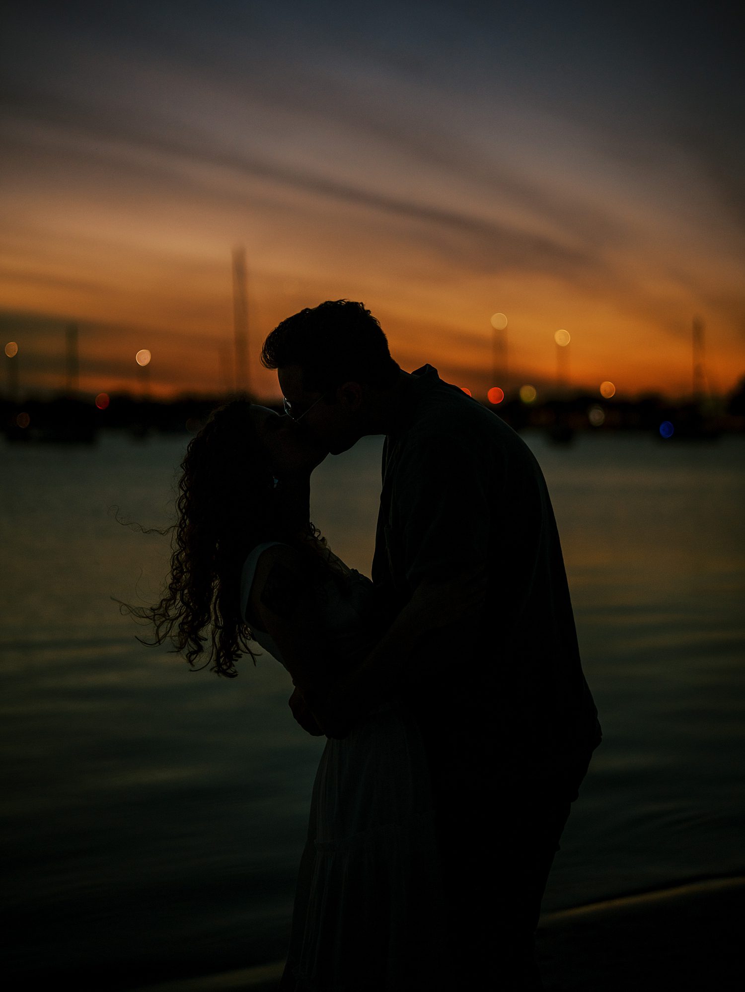 man and woman kiss under orange and red sunset on Davis Island Beach 