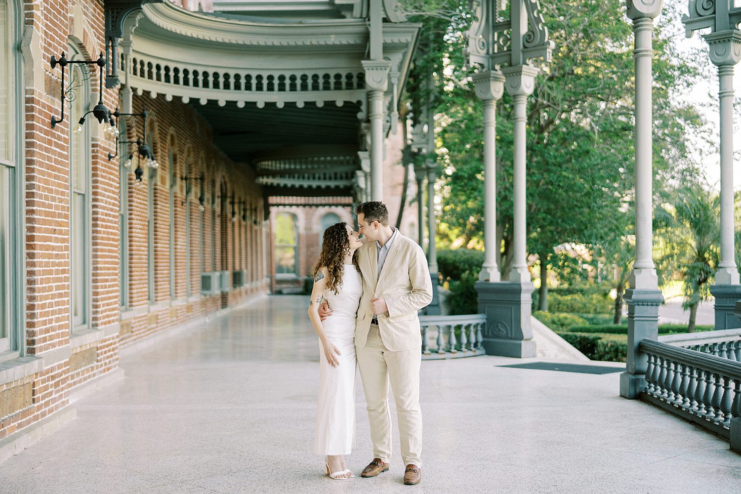 engaged couple hugs in classy attire on porch of the University of Tampa