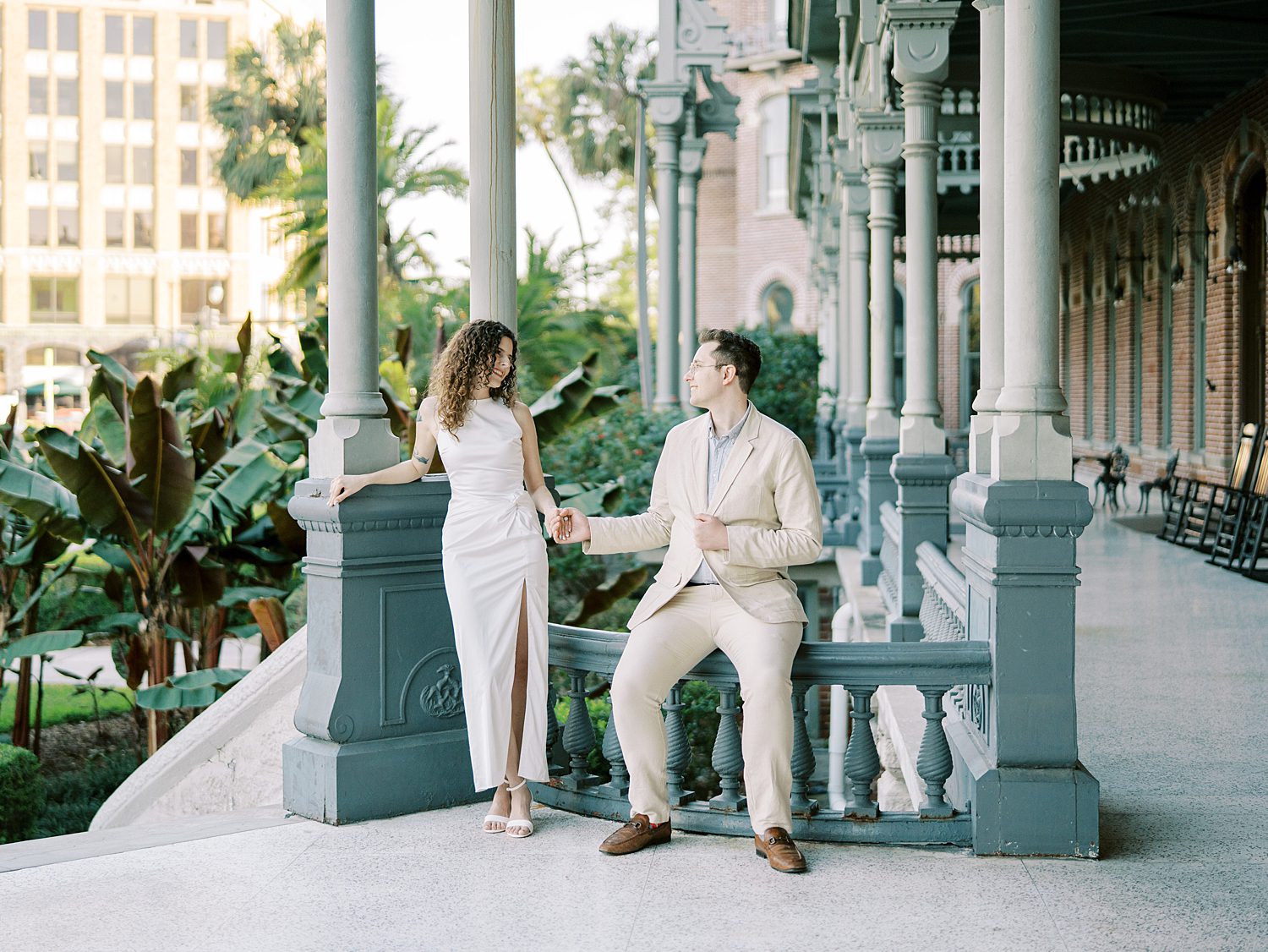 engaged couple leans against railing holding hands during University of Tampa engagement session