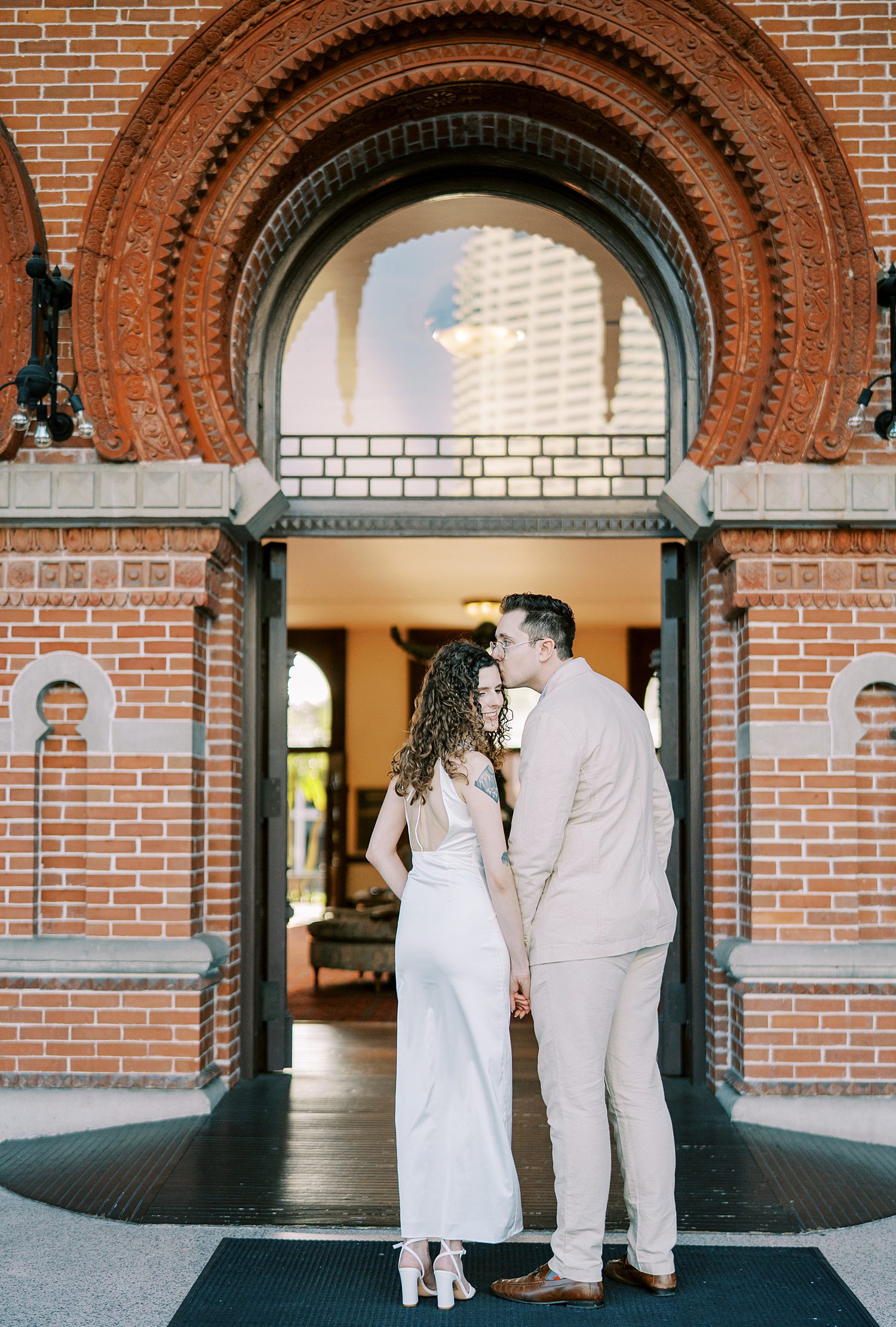 man kisses woman's forehead walking through brickwork way at the University of Tampa