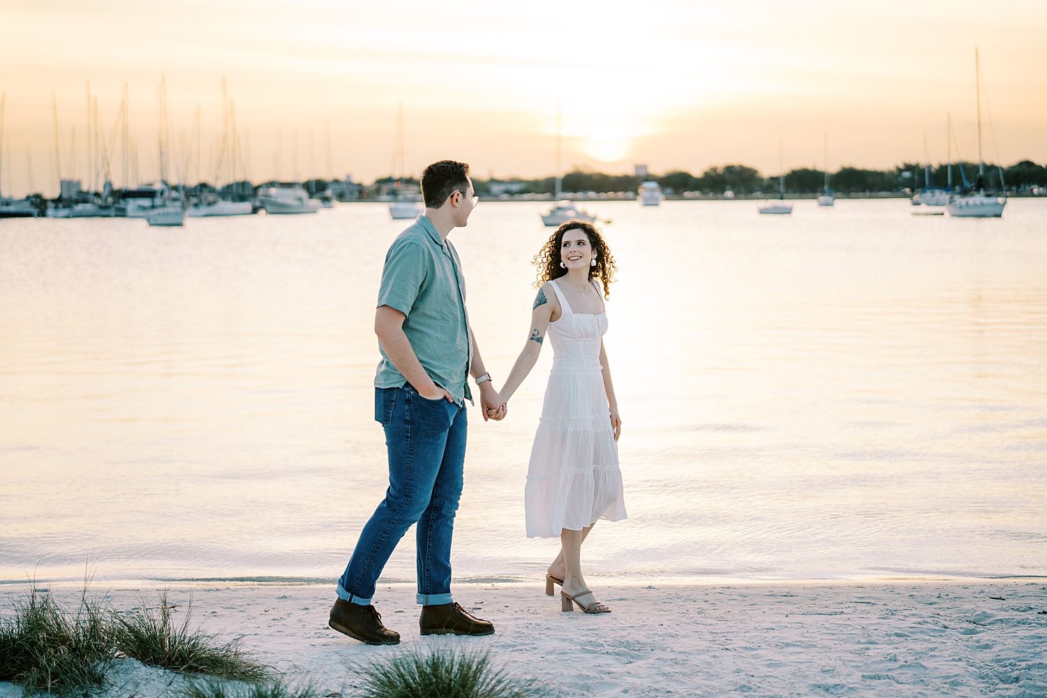 engaged couple holds hands walking on edge of beach in Tampa FL