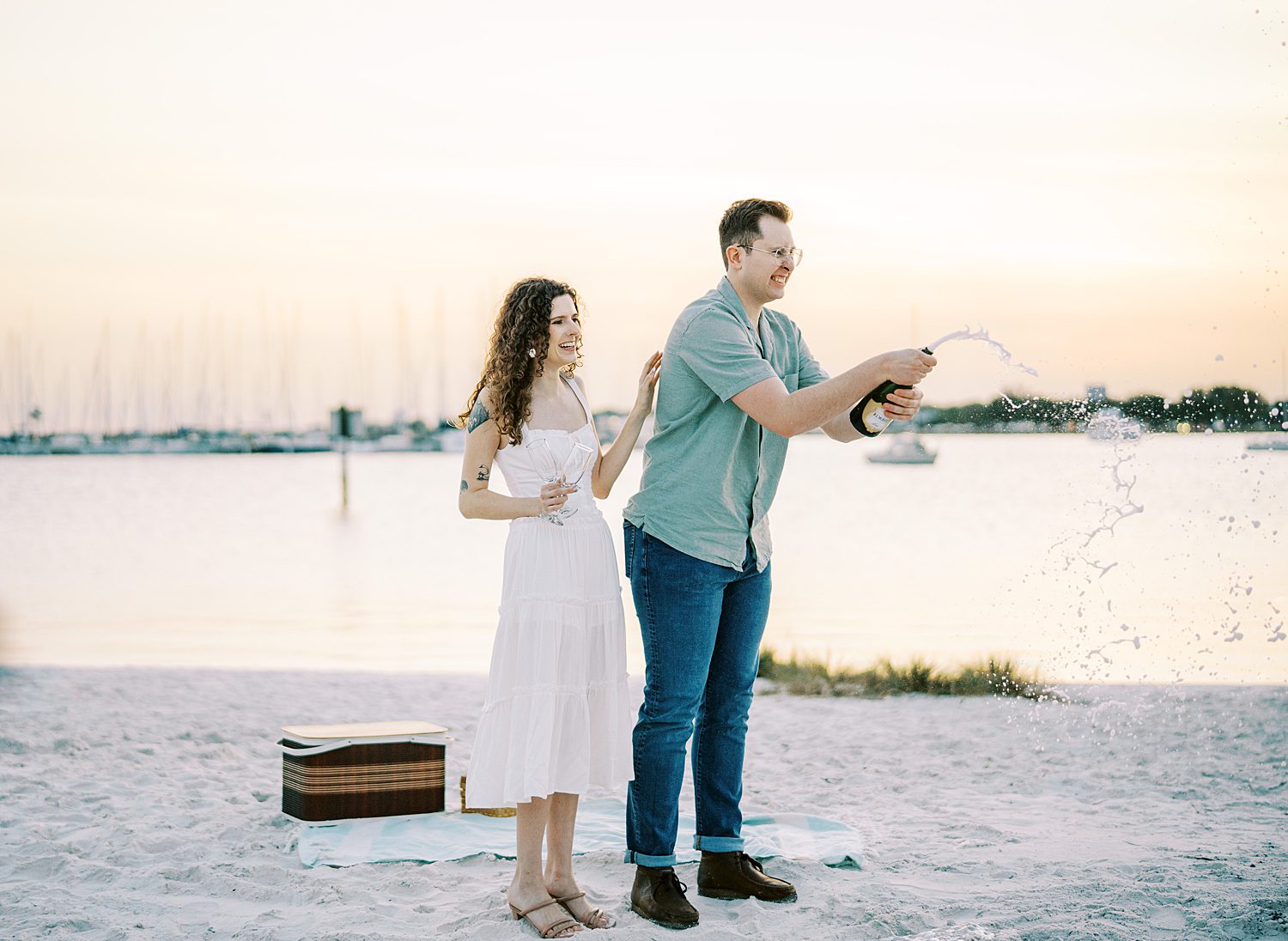 couple pops bottle of champagne at sunset on Davis Island Beach 