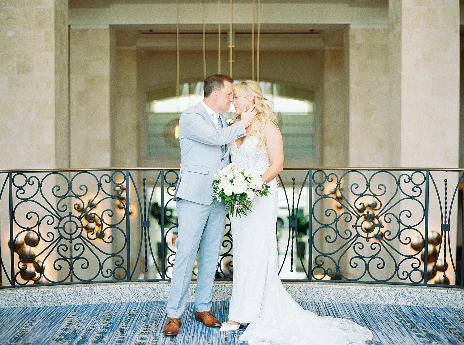 groom holds bride's chin kissing her in hallway at Armature Works