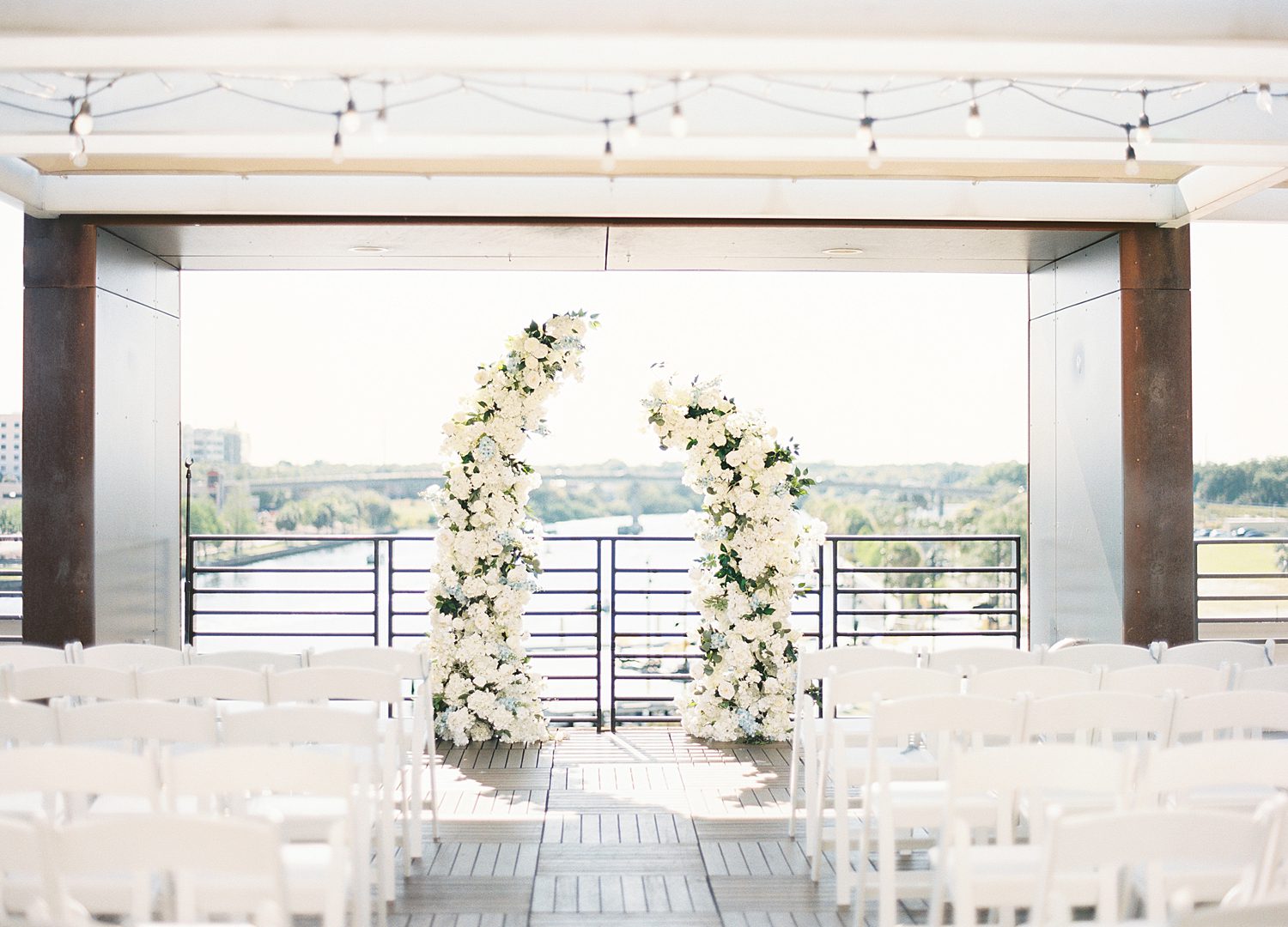 white floral arbors at end of aisle of rooftop at Armature Works