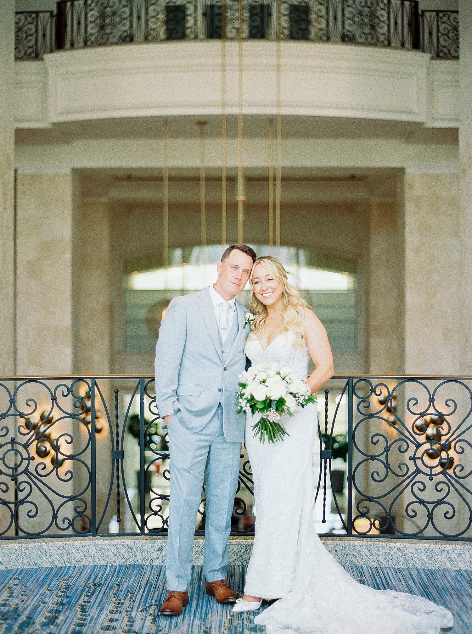 bride hugs groom in light blue suit on balcony in Tampa FL hotel