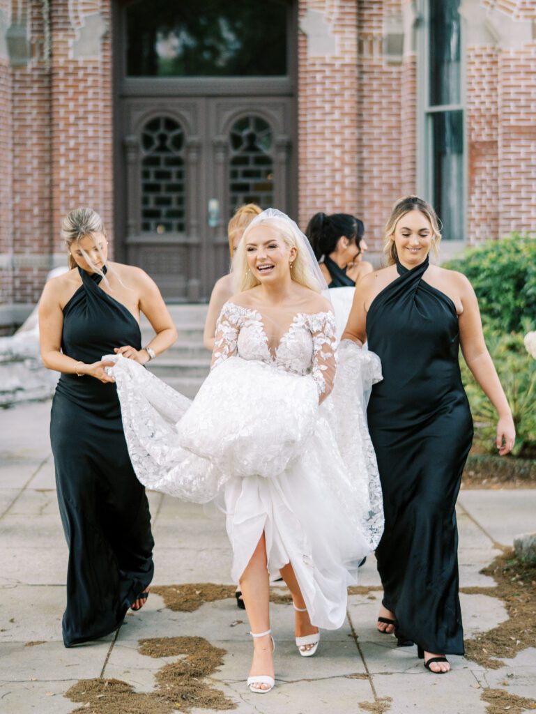 Bridesmaids holding drives dress to help her walk on her wedding day