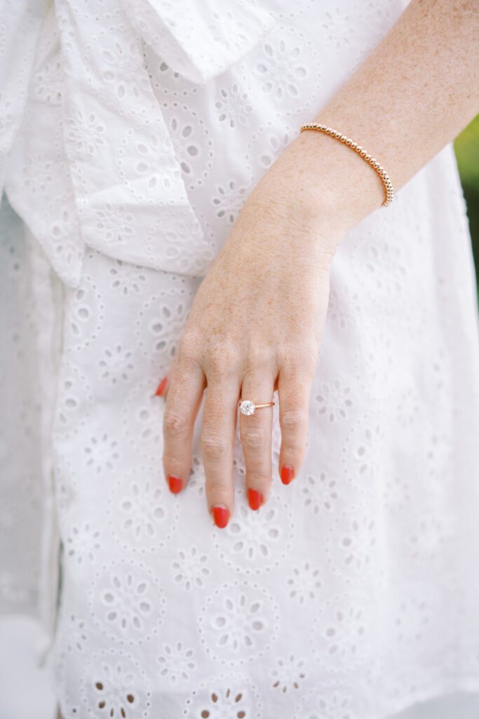Bride's engagement ring against her white dress